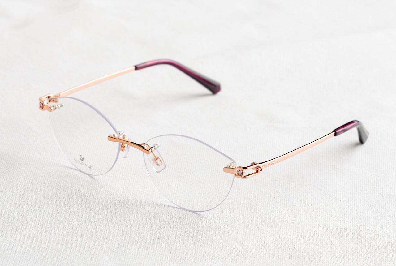 services-03 Close-up of stylish rimless eyeglasses with golden temples on a white background.